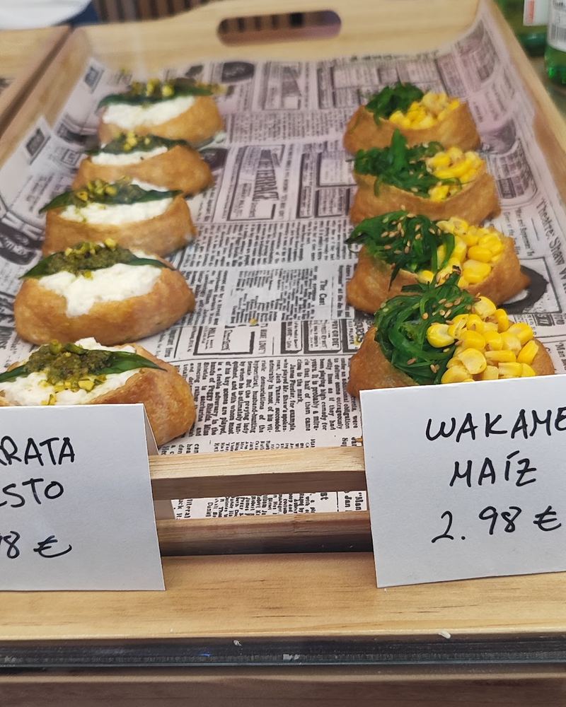 Bandeja de inari con wakame y maíz en la vitrina, con su cartel de precio