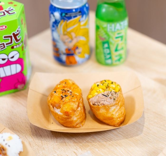 Refrescos japoneses, una caja de galletas y dos inari sobre la mesa