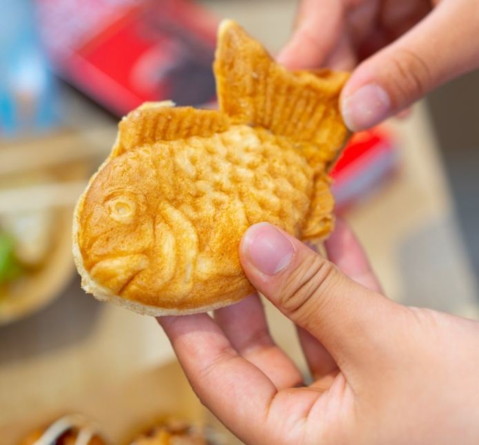Taiyaki dorado con forma de pez sujeto con las manos