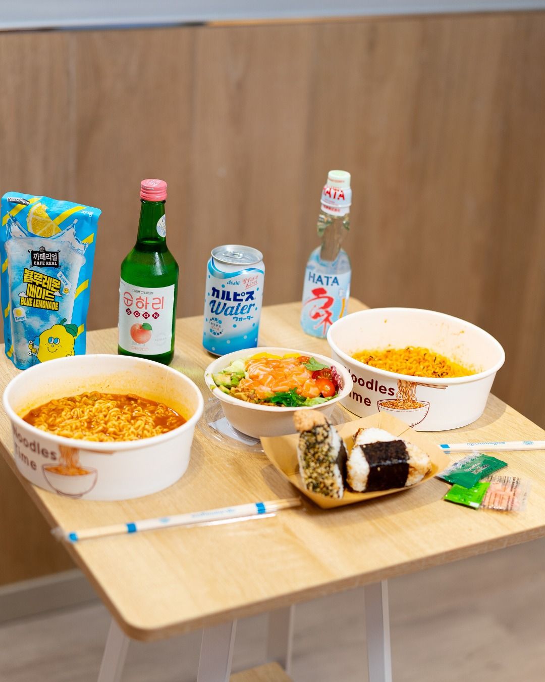 Mesa con dos ramen coreanos recién hechos, onigiris y bebidas asiáticas
